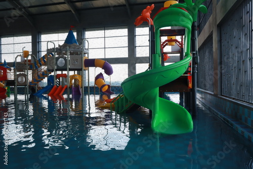 Fototapeta Naklejka Na Ścianę i Meble -  Children's Playground with Yellow and Blue Plastic Sliders at the Aquapark Swimming Pool