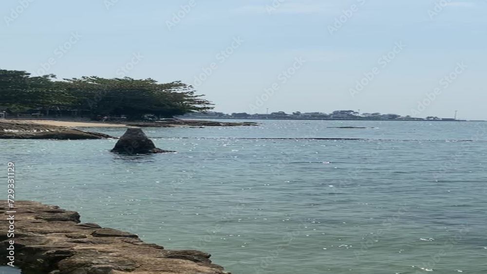 vertical view of seaside with rocks and city far away vertical view of seaside with rocks and city far away