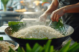 Visualize fragrant jasmine rice being rinsed and then soaked in rich coconut milk, alongside knotted pandan leaves and a pinch of salt.