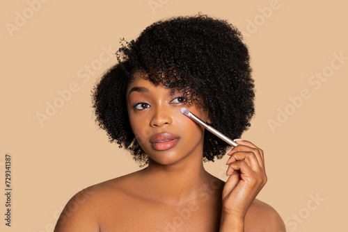 Woman applying eye makeup with brush, neutral tone