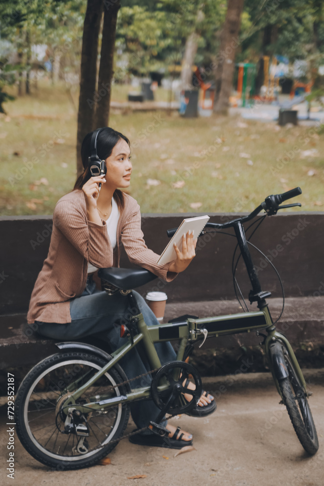 Happy young Asian woman while riding a bicycle in a city park. She smiled using the bicycle of transportation. Environmentally friendly concept. Happy young Asian woman while riding a bicycle in a city park. She smiled using the bicycle of transportation. Environmentally friendly concept.