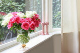 Vase with beautiful bouquet of roses and candles on windowsill indoors, space for text