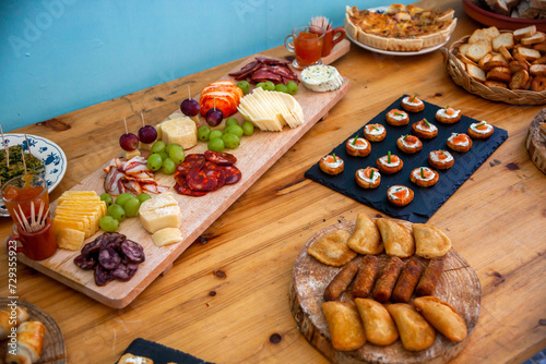 Fototapeta Naklejka Na Ścianę i Meble -  Festive table adorned with delicious Portuguese appetizers: quiches, rissois, pastries, assorted cheeses, and cured meats. A celebration of authentic and traditional flavors from Portugal.