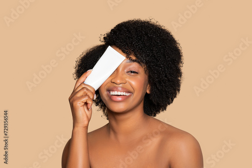 Happy black woman with cream tube, skincare joy