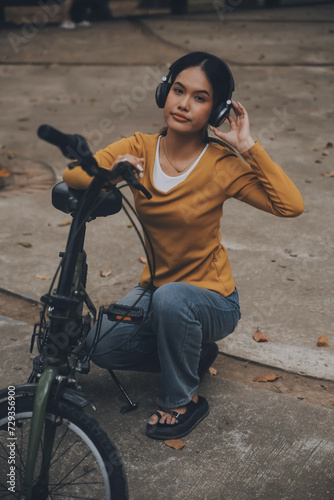 Happy young Asian woman while riding a bicycle in a city park. She smiled using the bicycle of transportation. Environmentally friendly concept.