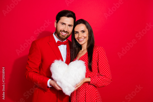 Portrait of lovely peaceful partners arms hold comfy fluffy heart figure pillow empty space isolated on red color background
