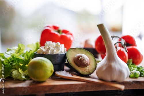 Healthy vegetables and fresh ingredients on wooden cutting board in front of bright kitchen window. Healthy nutrion concept for a spring diet. Space for text. photo