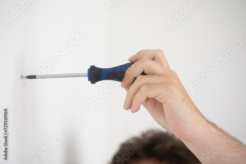 hand of a man putting a screw with screwdriver