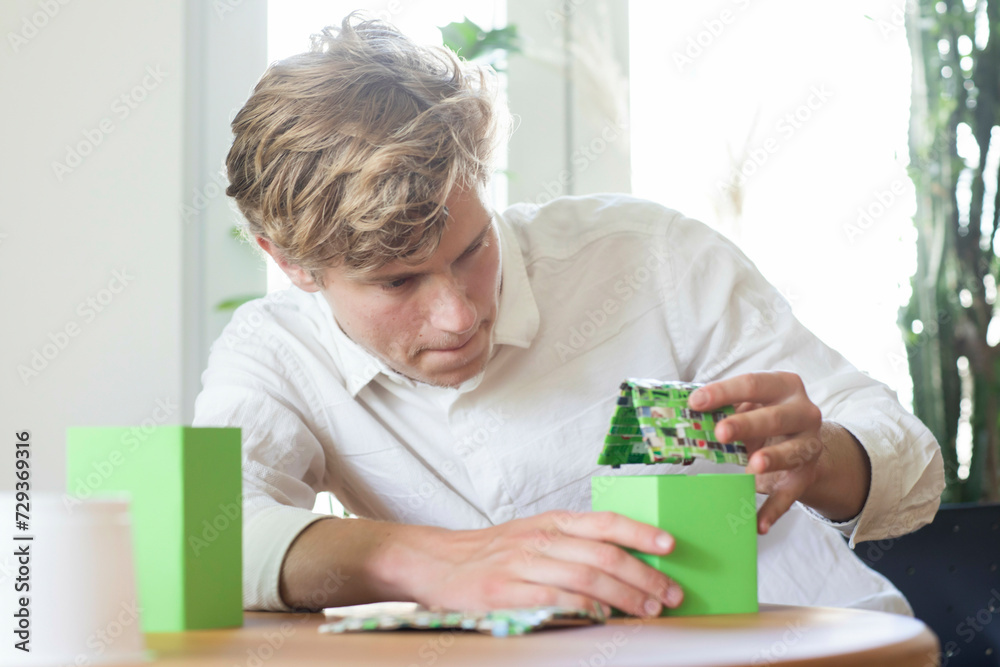 Young man building a green energy house model Young man building a green energy house model
