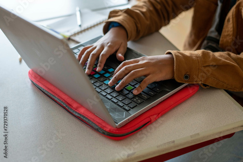Close up of a mixed raced student working on his laptop in class 