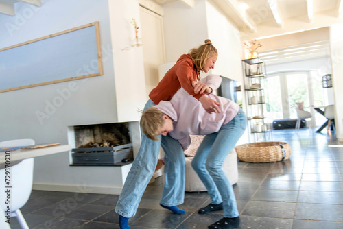 Brother and sister play fighting in their modern living room bright and aery  photo