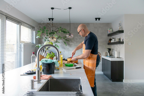 Adult man preparing mince for a lasagne in his modern kitchen photo