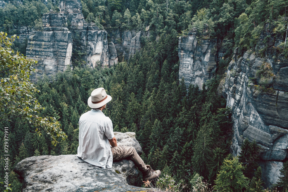 Mann sitzt auf Felsen und schaut in die Ferne, Elbsandsteingebirge, Sachsen, Deutschland