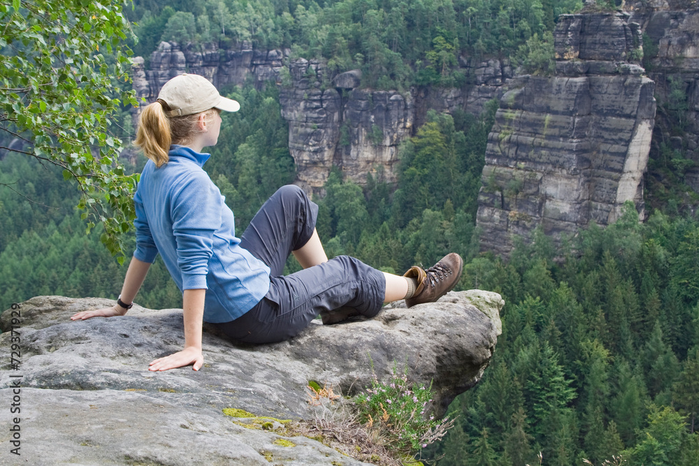 Frau sitzt auf Felsen und schaut in die Ferne, Elbsandsteingebirge, Sachsen, Deutschland