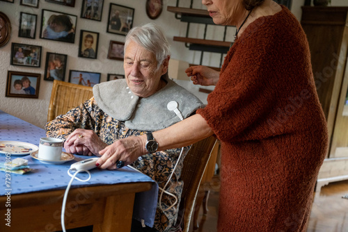 Elderly lady having her blood pressure check by a friend at home  photo