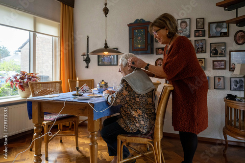 Elderly lady having her blood pressure check by a friend at home  photo