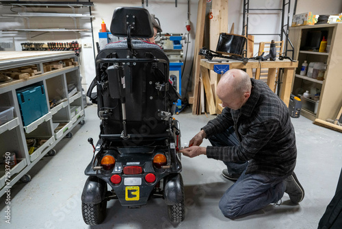 Mechanic working on mans prototype wheelchair  photo