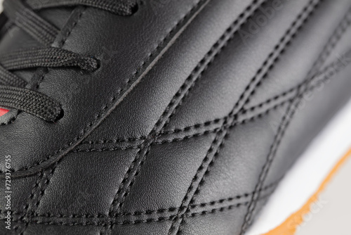 Part of a black leather sneaker with stitching close-up.