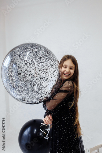 A little girl celebrates her 10th birthday. A girl on a white background in a black dress with long straight hair. Party, holiday
