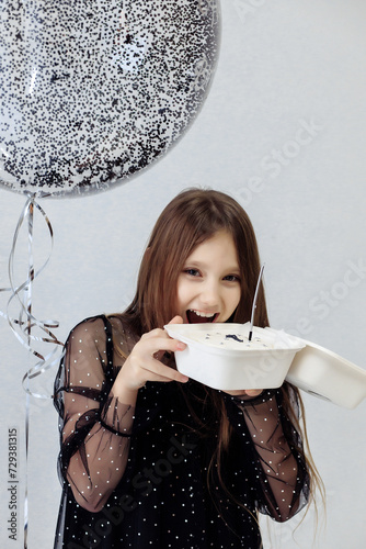 A little girl celebrates her 10th birthday. A girl on a white background in a black dress with long straight hair. Party, holiday