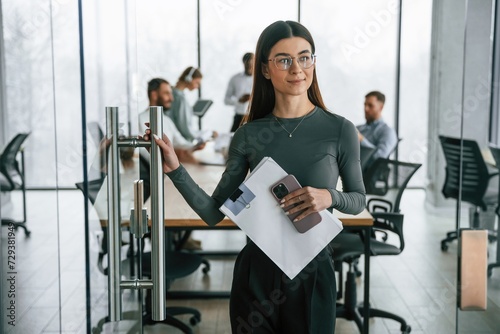 Young woman in glasses, portrait. Team of office workers are together indoors