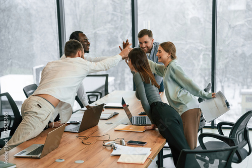 Celebrating success, giving high five. Team of office workers are together indoors photo