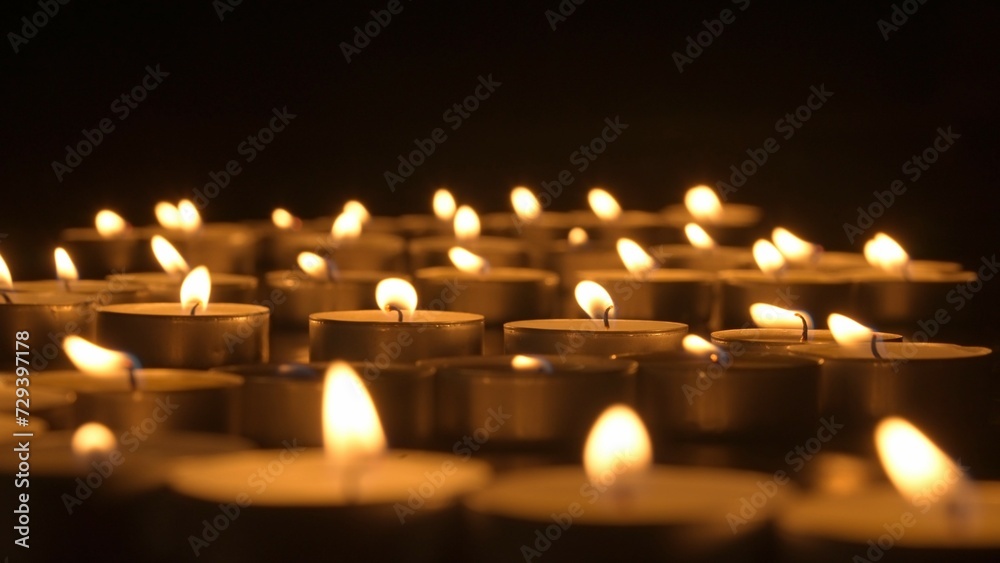 Rows of burning candles. The candles burn against a black backgrounds. The concept of a memorial day. Background for advertising and design projects. Rows of burning candles. The candles burn against a black backgrounds. The concept of a memorial day. Background for advertising and design projects.