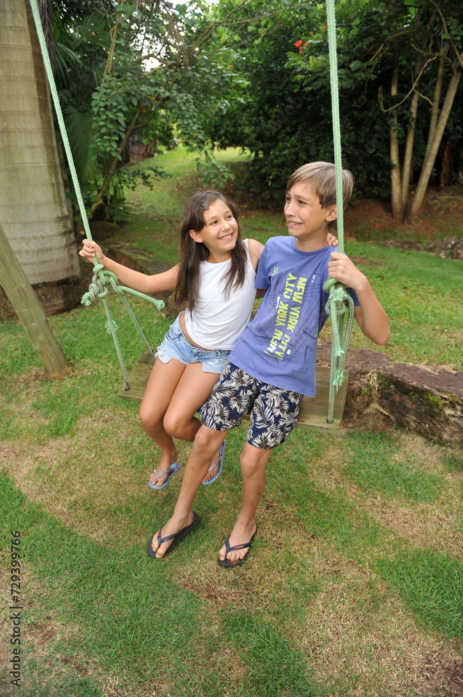 Fototapeta premium irmãos brincando em balanço no parque , férias escolares 