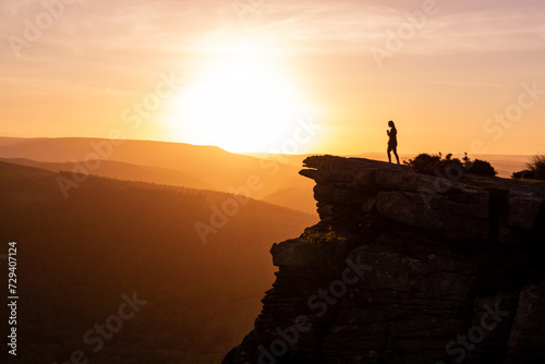 silhouette of a person standing on a rock sunset