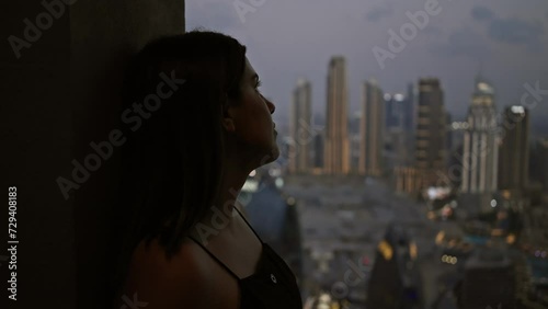 Silhouetted woman gazes contemplatively at the dubai skyline during twilight from a high view observatory. photo