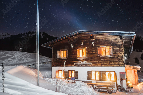 Cabin in snow buried in snow in the winter with the lights on. Achenkirch, Austria photo