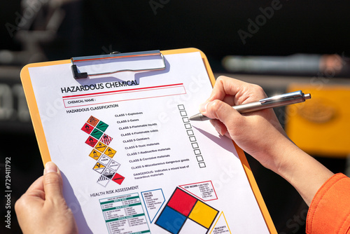 Action of an engineer is checking on chemical hazardous material checklist form with background of train freight tanker for crude oil or chemical cargo. Industrial safety working scene.  photo