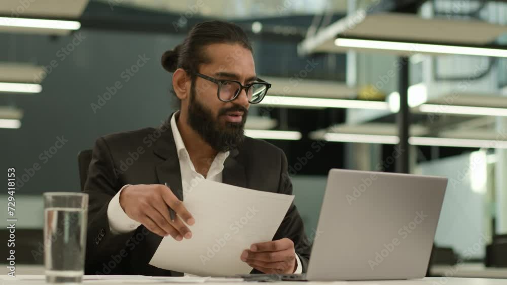 Serious Muslim man Indian business leader male CEO manager employer Arabian businessman entrepreneur distant coach consultant with paper documents report contract talk laptop video call in office