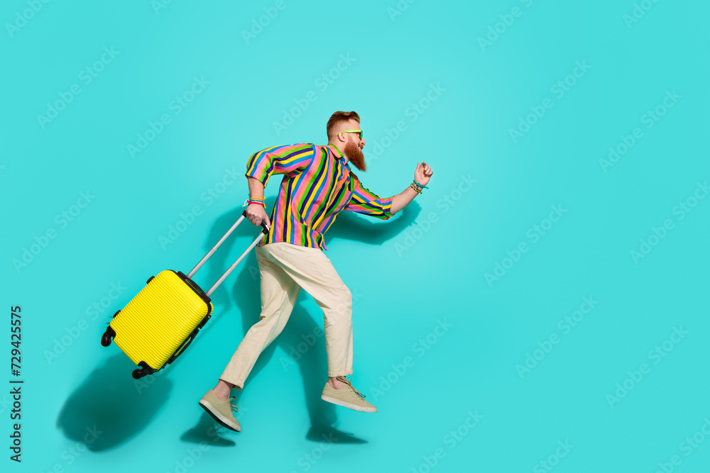 Full body length photo of running man tourist with yellow suitcase empty space hurry up to airport isolated on cyan color background Full body length photo of running man tourist with yellow suitcase empty space hurry up to airport isolated on cyan color background