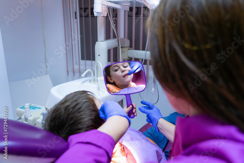 Dentist woman showing a child his teeth with a mirror in the office