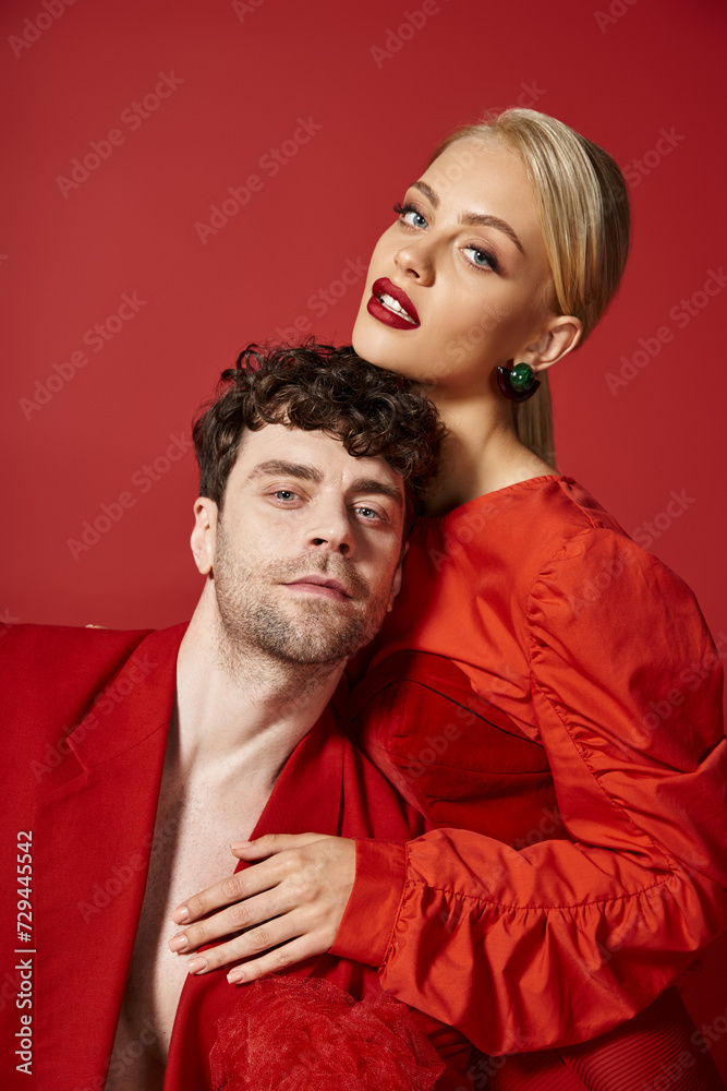 beautiful young woman with red lips and blonde hair embracing good looking man in red attire, style beautiful young woman with red lips and blonde hair embracing good looking man in red attire, style