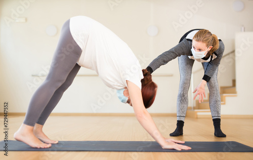 Pregnant woman practices yoga with an instructor wearing an antiviral mask during quarantine photo