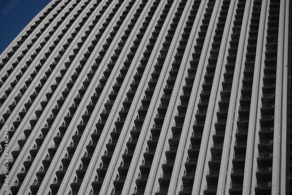 white, grey facade full of balconies. Balconies Of The Facade Of The Building. fragment of a facade of a building with balcony on blue sky background. white, grey facade full of balconies. Balconies Of The Facade Of The Building. fragment of a facade of a building with balcony on blue sky background.