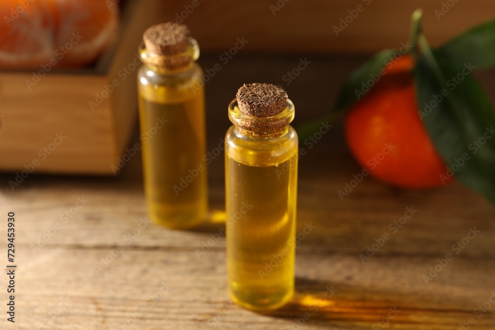Bottles of tangerine essential oil on wooden table, closeup Bottles of tangerine essential oil on wooden table, closeup