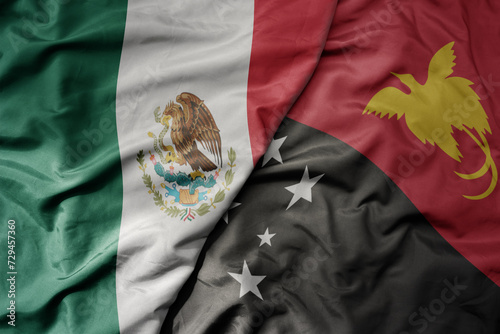 big waving national colorful flag of Papua New Guinea and national flag of mexico .