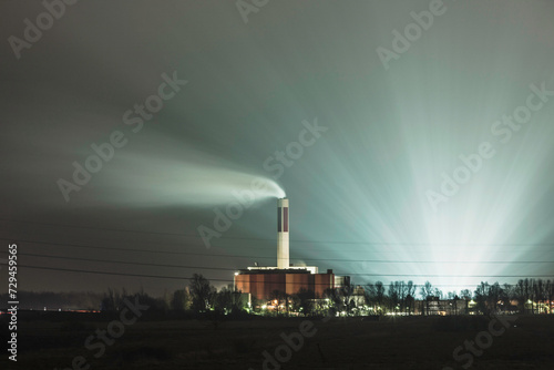Nightscape landscape of cooling tower from a factory with fog and light installation behind. Bremerhaven, Germany photo