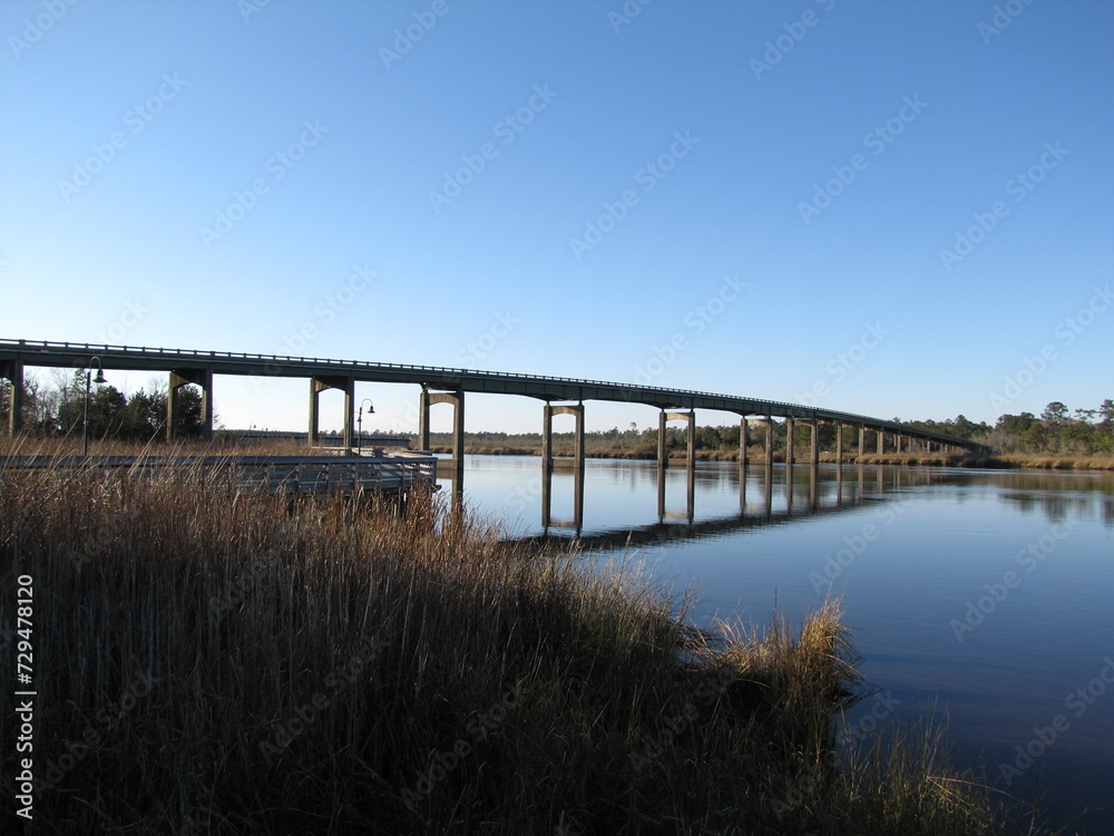 Vast bridge extends over a serene river, surrounded by lush vegetation
