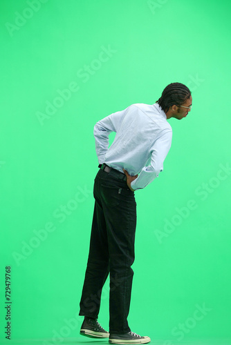 A man in a gray shirt, on a green background, full-length, look at distance