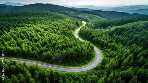 Aerial top view of a beautiful curved road on green forest in the rainy season.
