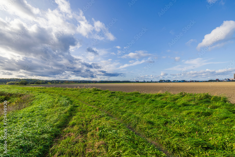 Beautiful view of pathway winding on green grass along plowed farmland, against backdrop of blue sky with clouds. Sweden. Beautiful view of pathway winding on green grass along plowed farmland, against backdrop of blue sky with clouds. Sweden.