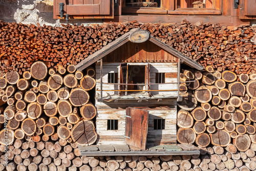 Wooden model house covered by sorted firewood in remote alpine village of Sauris di Sotto in Carnic Alps, Friuli Venezia Giulia, Italy. Serene tranquil atmosphere in Italian Alps. Split logs stacked photo