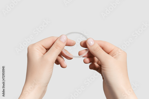 female hands holding hormonal contraceptive ring isolated on grey background photo