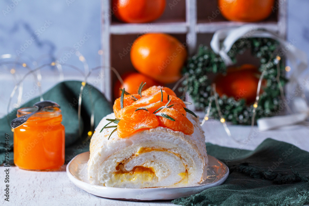 Meringue roll filled with mascarpone, cream and tangerine jam on a background of tangerines and a green heart.