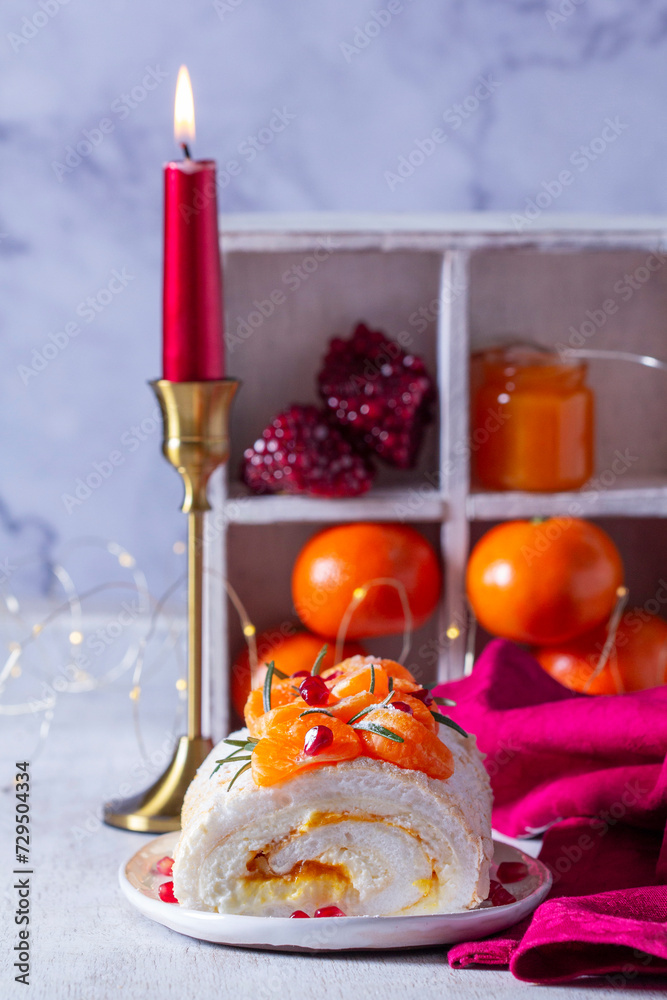 Meringue roll filled with mascarpone, cream and tangerine jam, decorated with tangerines and pomegranate seeds.