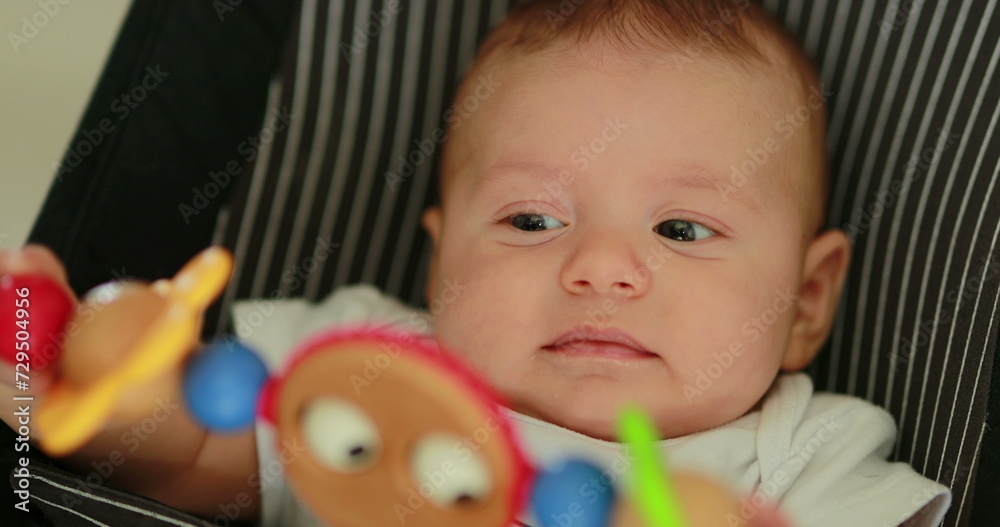 Obraz premium Baby newborn in chair seated with spinning toy in the foreground